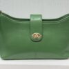 Green leather handbag with a gold turn-lock clasp and strap visible on sides, photographed against a light backdrop.