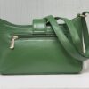 Green leather handbag with a gold zipper and strap resting on a white surface.