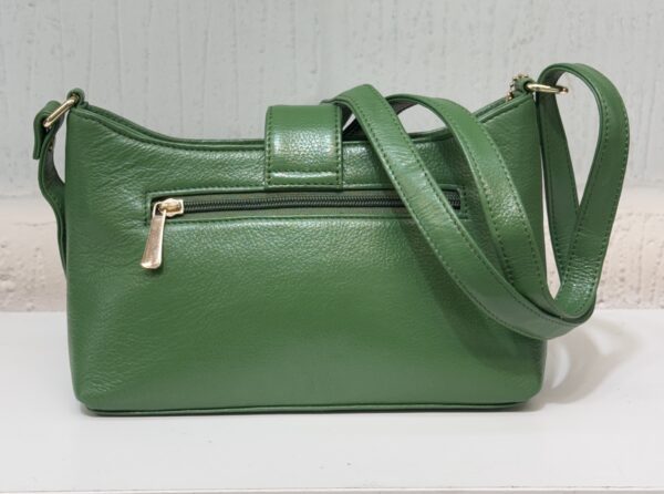 Green leather handbag with a gold zipper and strap resting on a white surface.