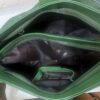 Open green handbag showing inner zipper compartments and dark lining