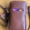 Maroon textured leather crossbody bag with a front card slot showing a purple card partially tucked in