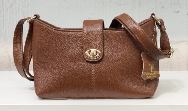 Brown pebbled leather handbag with a gold turn-lock closure and a long shoulder strap on a white surface.