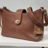 Brown pebbled leather handbag with gold hardware and a small tag reading BORN TO HER LONDON on the front.