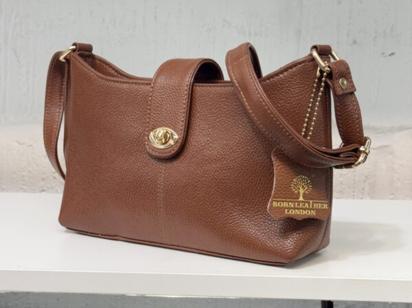 Brown pebbled leather handbag with gold hardware and a small tag reading BORN TO HER LONDON on the front.