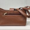 Brown textured leather handbag with a front zip pocket and top strap hardware.