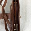 Brown leather handbag opened to show two inner zip compartments and gold hardware.