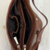 Brown leather handbag with multiple zip compartments opened to reveal dark fabric lining and interior pockets.