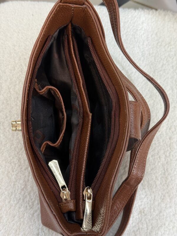 Brown leather handbag with multiple zip compartments opened to reveal dark fabric lining and interior pockets.